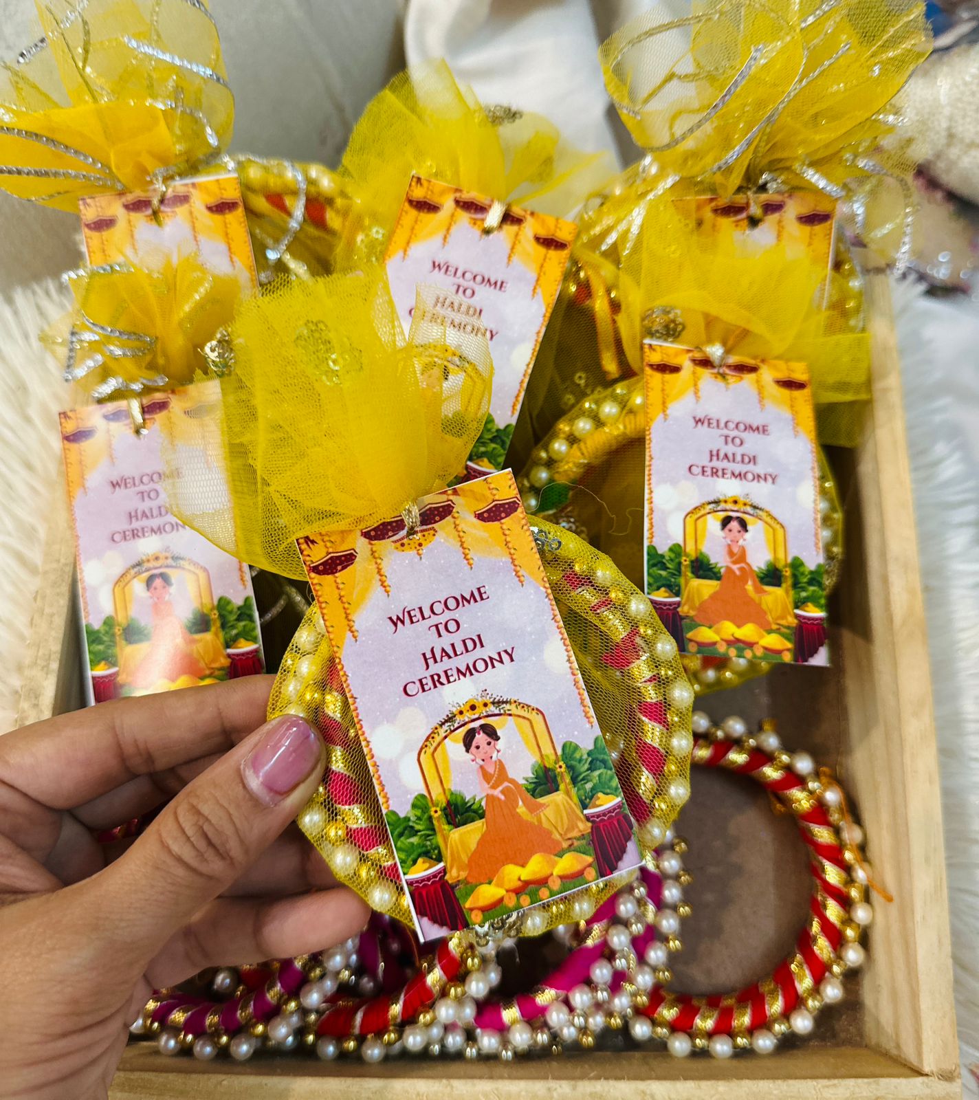 Yellow and white bangles with a "Welcome to Haldi Ceremony" tag attached, packaged as personalized Haldi favors for a traditional Indian wedding celebration, showcasing a custom name tag for each guest.