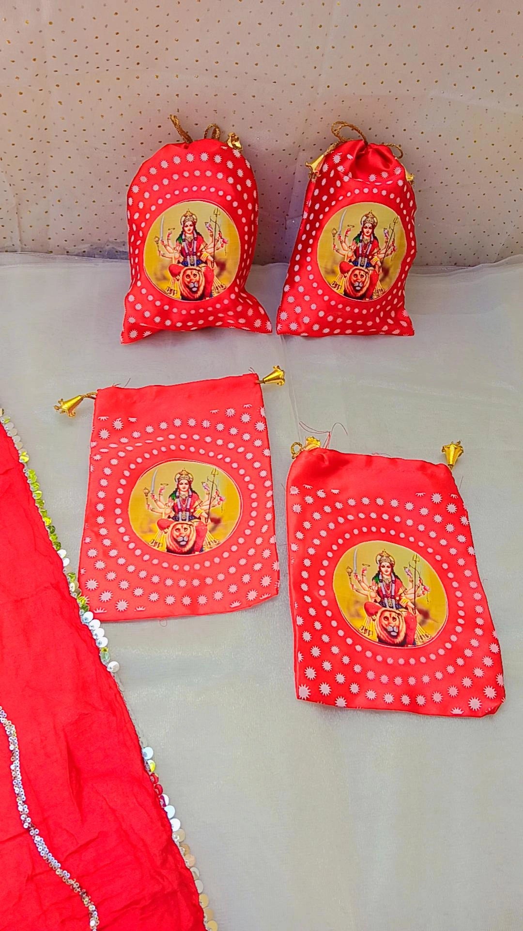 Red prasad potli bags with Goddess Lakshmi print, polka dot patterns, and golden drawstrings, ideal for puja and festive gifting.